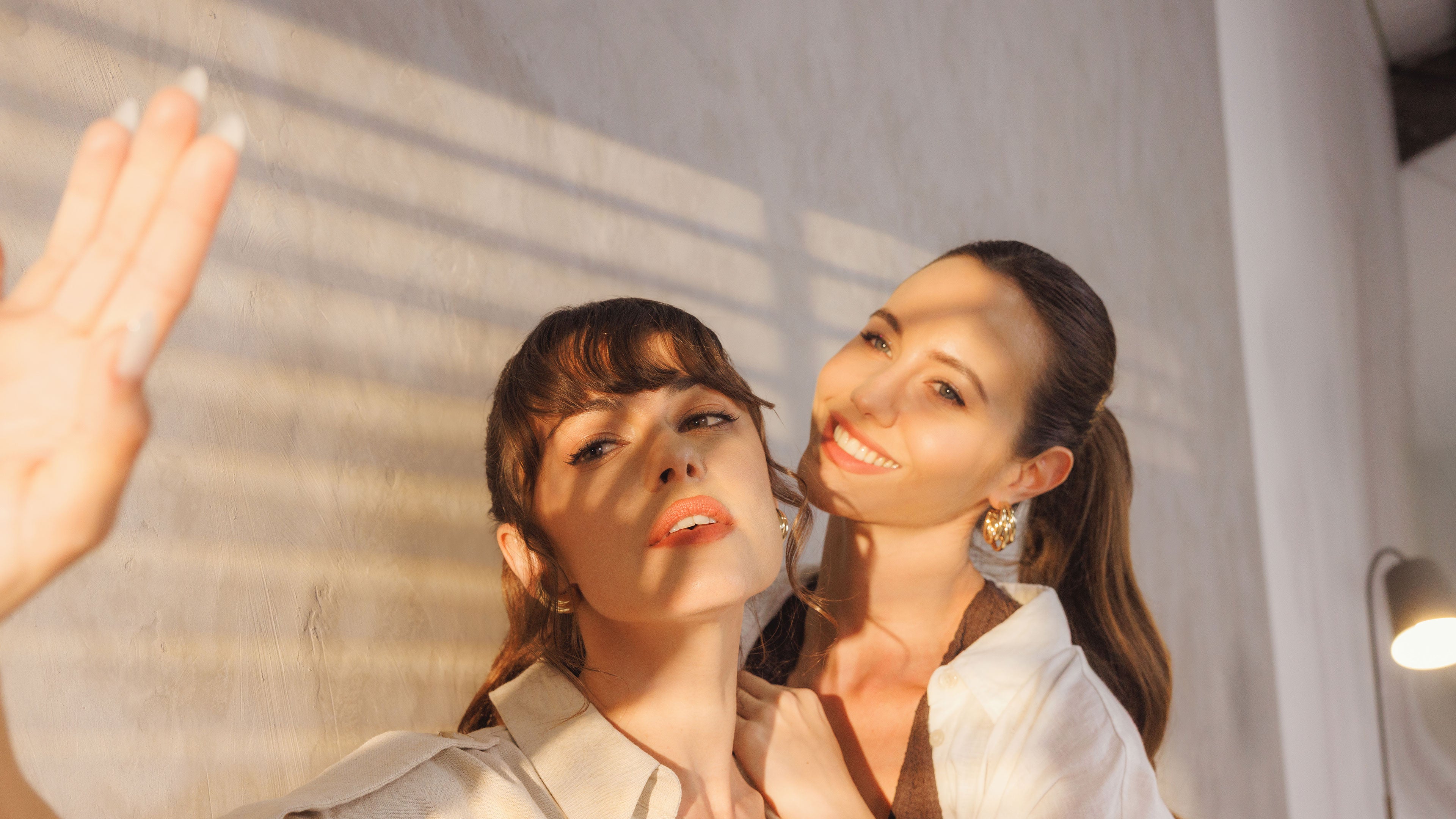 Two women posing together with a neutral background